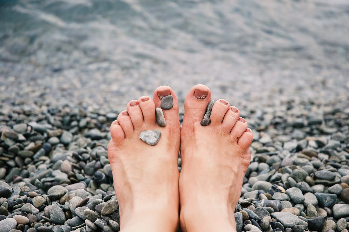 Unmasking Toe Nail Fungus: Lifestyle Factors and Causes Feet With Balanced Pebbles